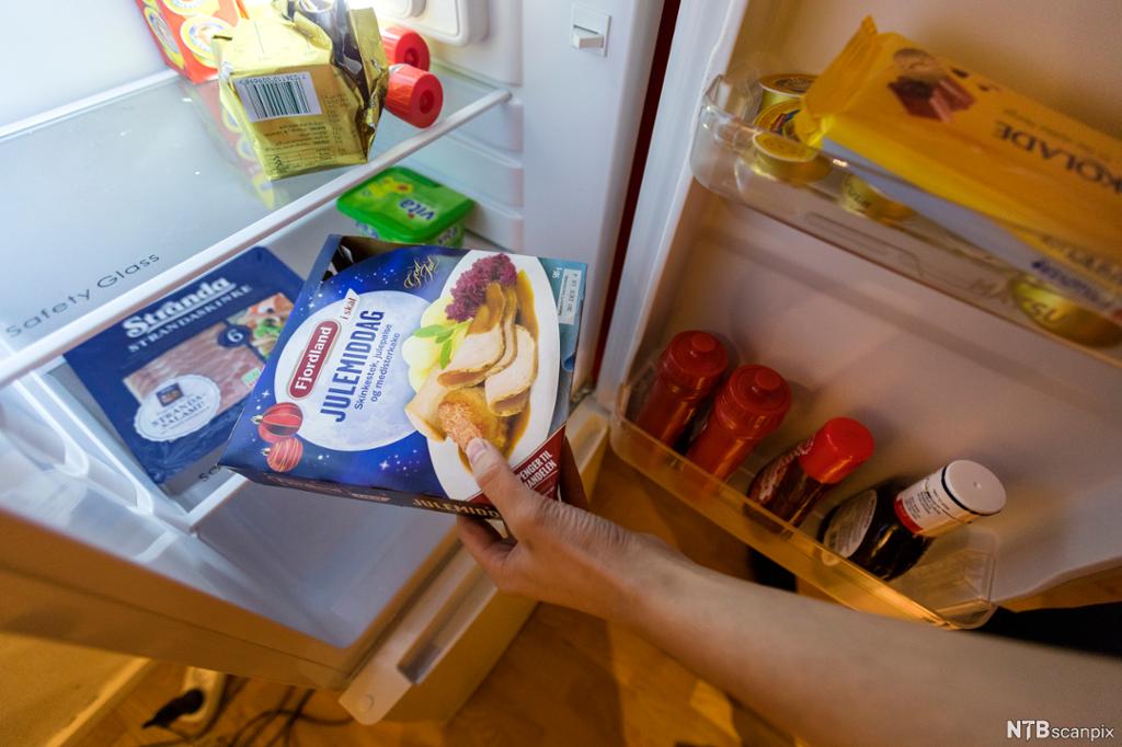Person henter ferdigmiddag i kjøleskap. Foto.