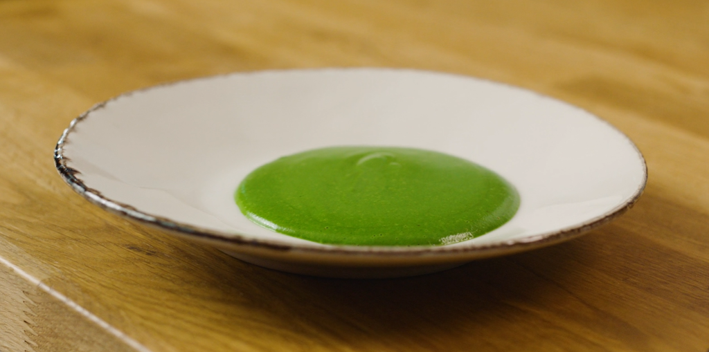 Ein spinatpuré med frisk grønfarge lagd opp på ein kvit tallerken. Foto.