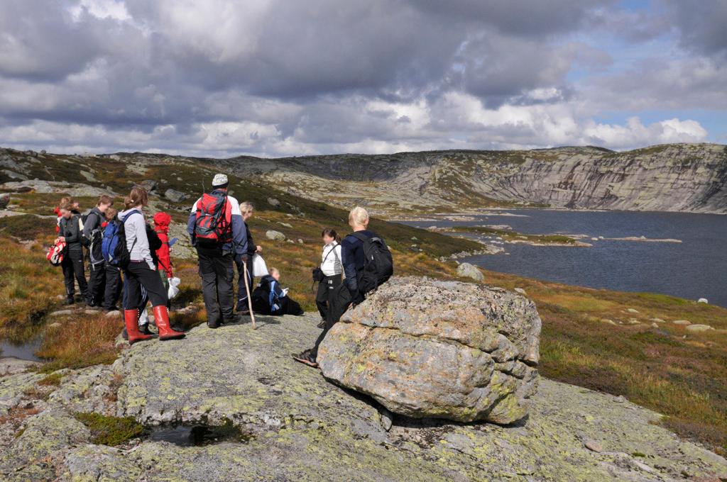 Turkledde ungdommar er samla ved ein stein i eit fjellandskap. Foto.