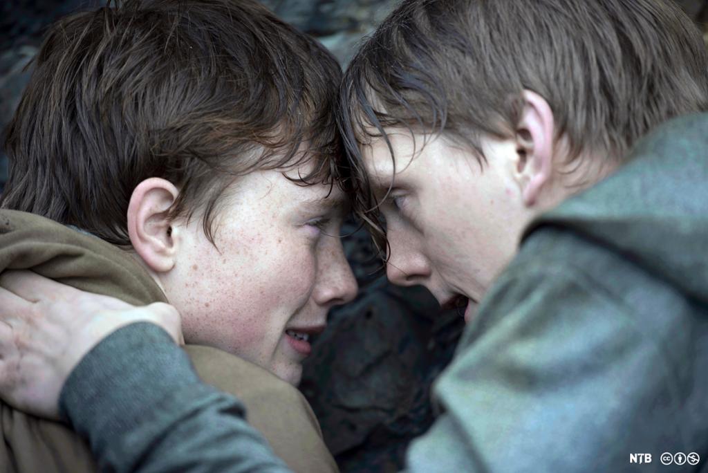 Nærbilde av to små, redde gutter som ligger på bakken. Fra opptak til filmen "22.juli".