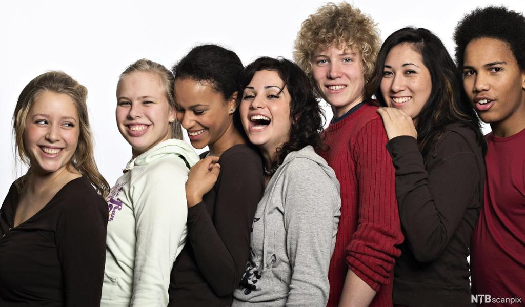 En gruppe ungdommer står tett sammen på rekke og smiler. Foto. 