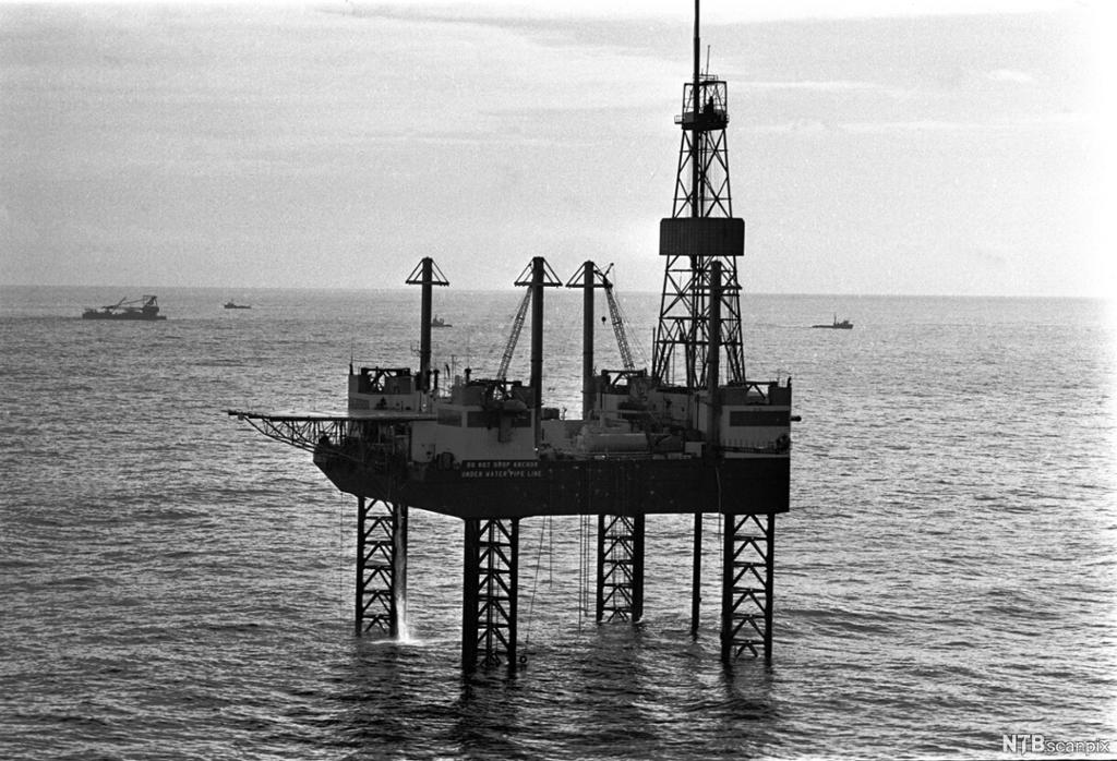 En oljeplattform ute i sjøen. Svart-hvitt foto.