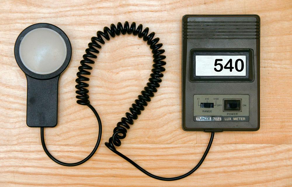 På en benk ligger et apparat som består av en svart boks med et par knapper og en skjerm som viser et tall. Til venstre ligger en sensor, som er koblet til apparatet med en svart spiralledning. Foto