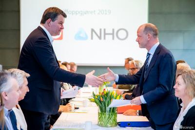LOs leder og NHOs sjef hilser på hverandre fra hver sin side av bordet under åpningen av forhandlinger i 2019. Foto.