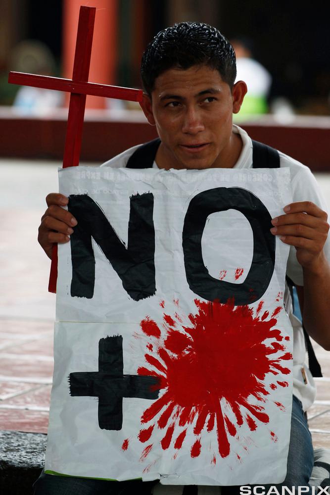 A Central American migrant, carrying a cross and a sign against violence, participates in a Via Crucis in Tapachula, Mexico, Wed