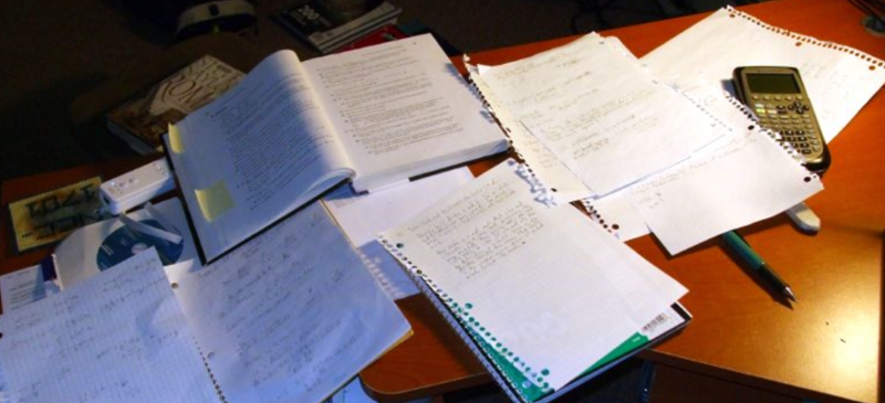 Skrivebord med masse papir og en kalkulator på. Foto