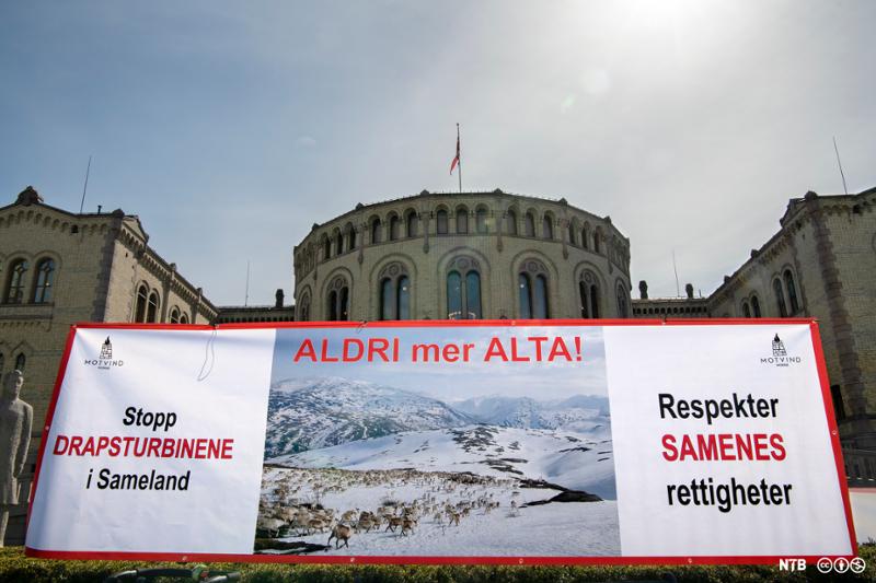 Banner med slagord mot vindmølleutbygging i Samland med Stortinget i bakgrunnen. Foto.