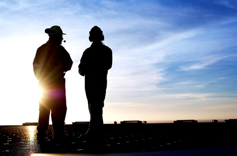 To arbeidere står på helikopterdekket og nyter solnedgangen. Foto.