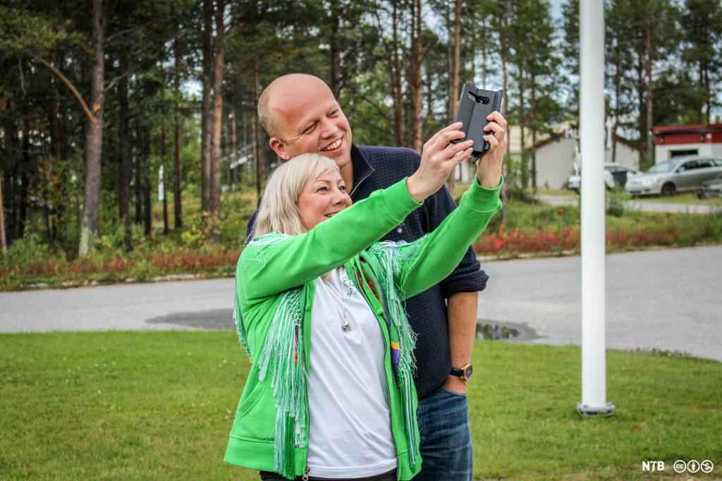 Mann og kvinne smiler bredt og tar en selfie med mobiltelefon. Foto.