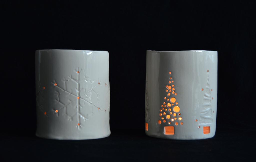 To sylinderformete telysholdere med stiliserte snøkrystaller og juletrær som dekor. Foto. 