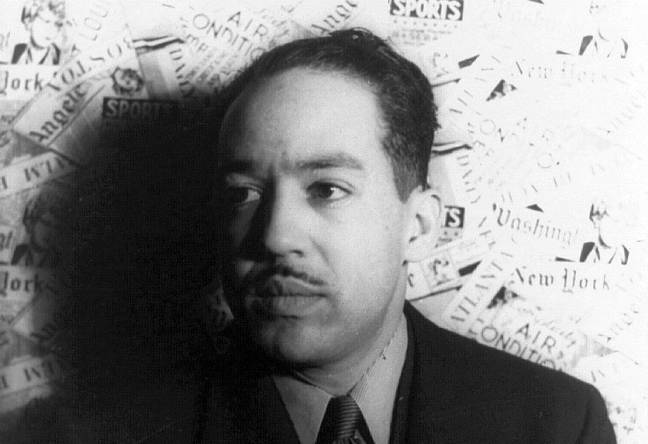 Photo: Langston Hughes is a middle aged man. He is wearing a suit. He has a thin moustach. 