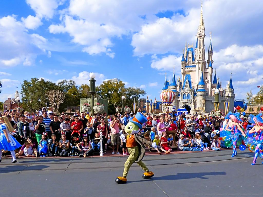 Parade i Disney World, Florida. Fleire tilskodarar ser på at Disney-figuren Timmy Grashoppe går forbi dei i paraden. Foto.