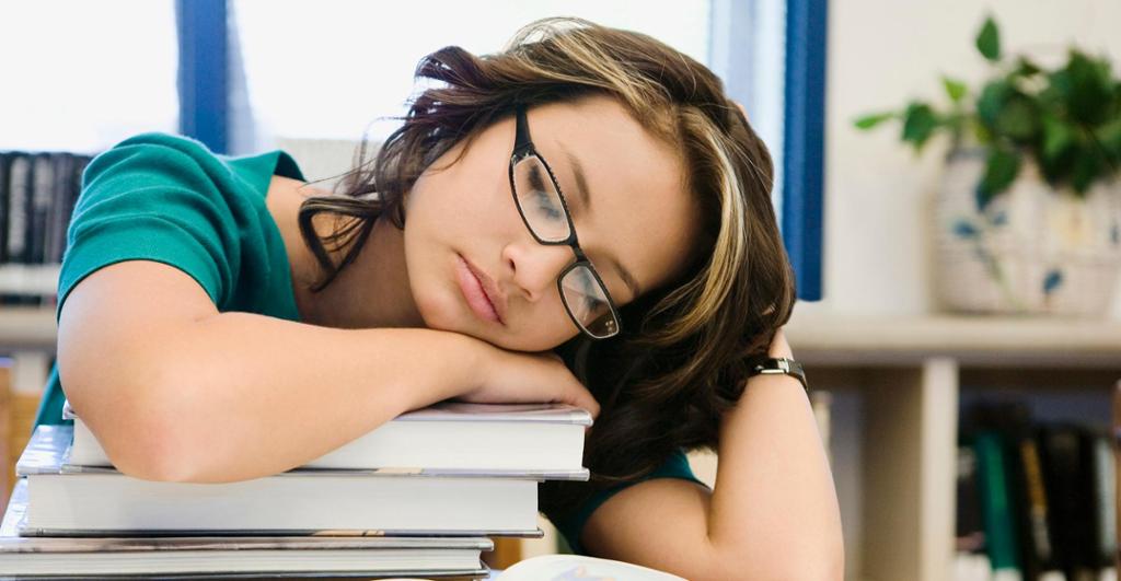 Teenage student sleeping over her books. 
