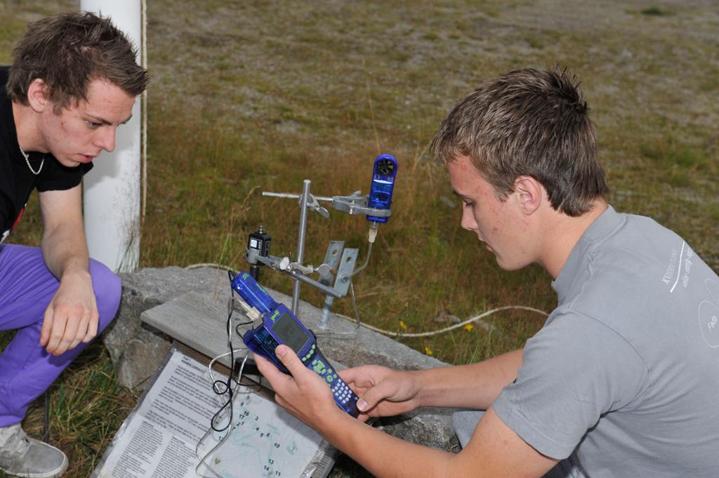 To gutar sit på huk og monterer ein dataloggar. Foto