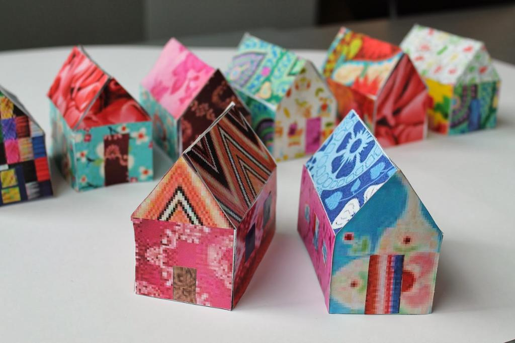 Fotografi av åtte små papirhus med ulike mønster i sterke farger.