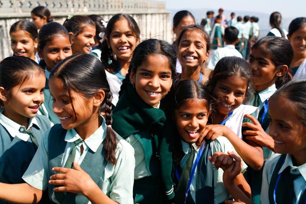 Photo: Group picture of  Indian school girls, all smiling and laughing. They are wearing school uniforms. 