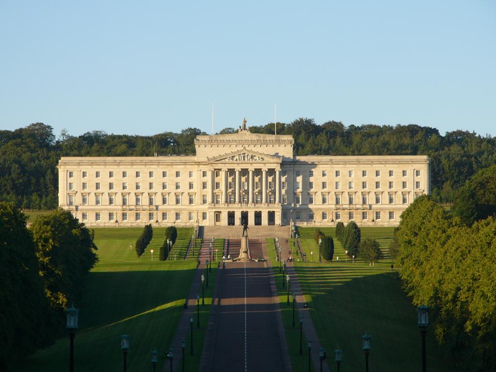 Photo: We see a large stone building in an old-fashioned style. It has a central part with stairs leading up to a front building with columns. 