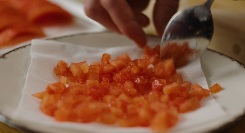 Flådde tomater skåret i små biter som tomatconcassé anrettet på tallerken. Foto.
