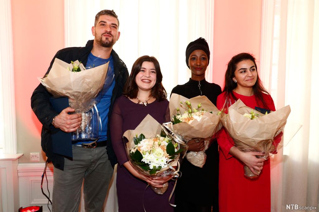 En mann og tre jenter med minoritetsbakgrunn med hver sin blomsterbukett. Foto.