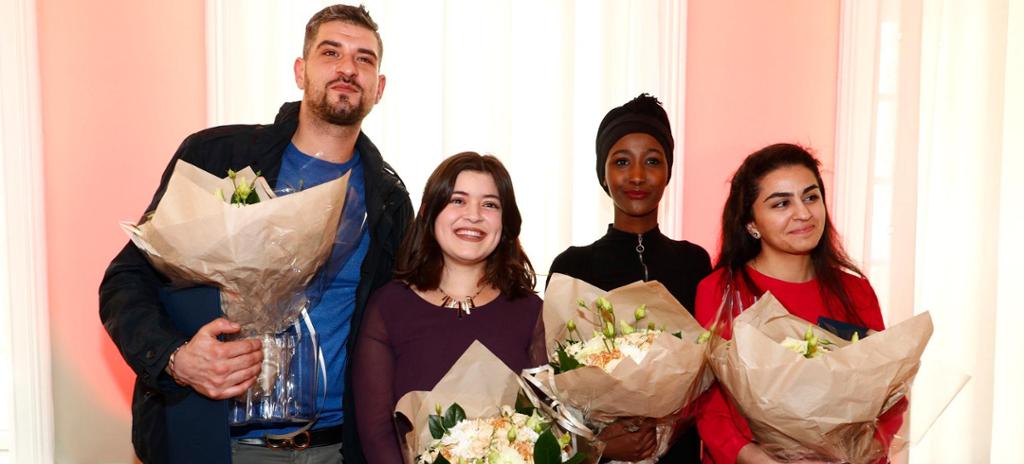 Foto av ein mann og tre unge kvinner med minoritetsbakgrunn. Alle fire held kvar sin blomsterbukett etter å ha fått ein pris. 