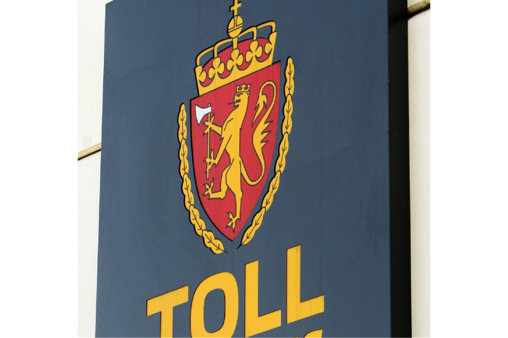 Skilt med logoen til Tolletaten. Det er ei løve på et skjold med ei krone og et kors på toppen. Foto.