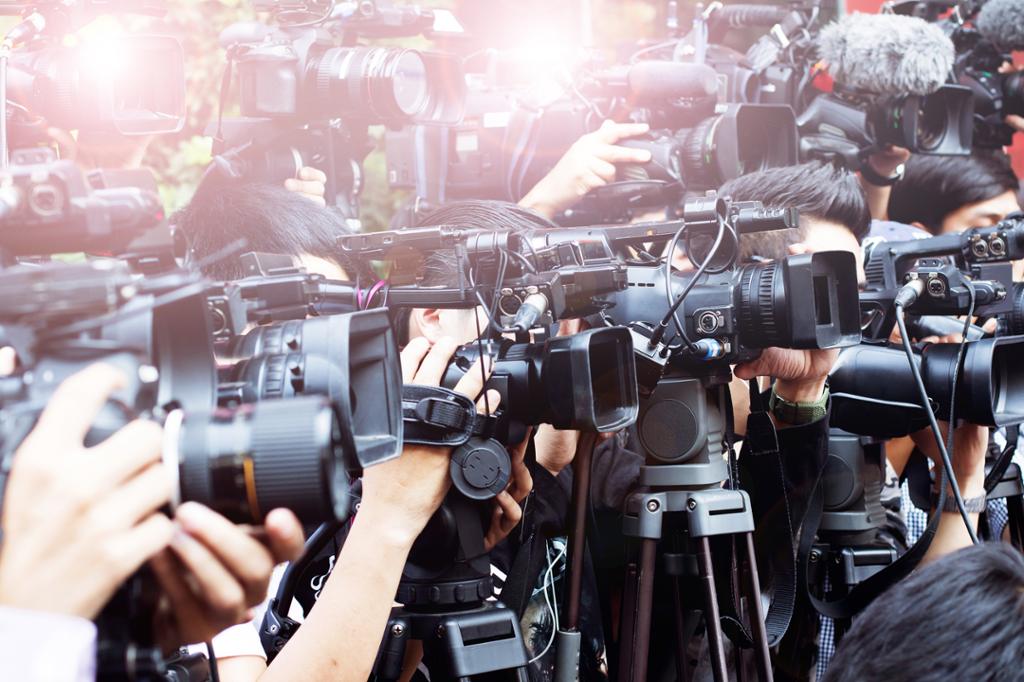 Et stort kobbel av journalister med foto- og videokameraer knipser i vei. Foto.