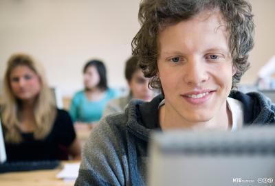 Gutt ser på skjerm i et klasserom og smiler. Foto.