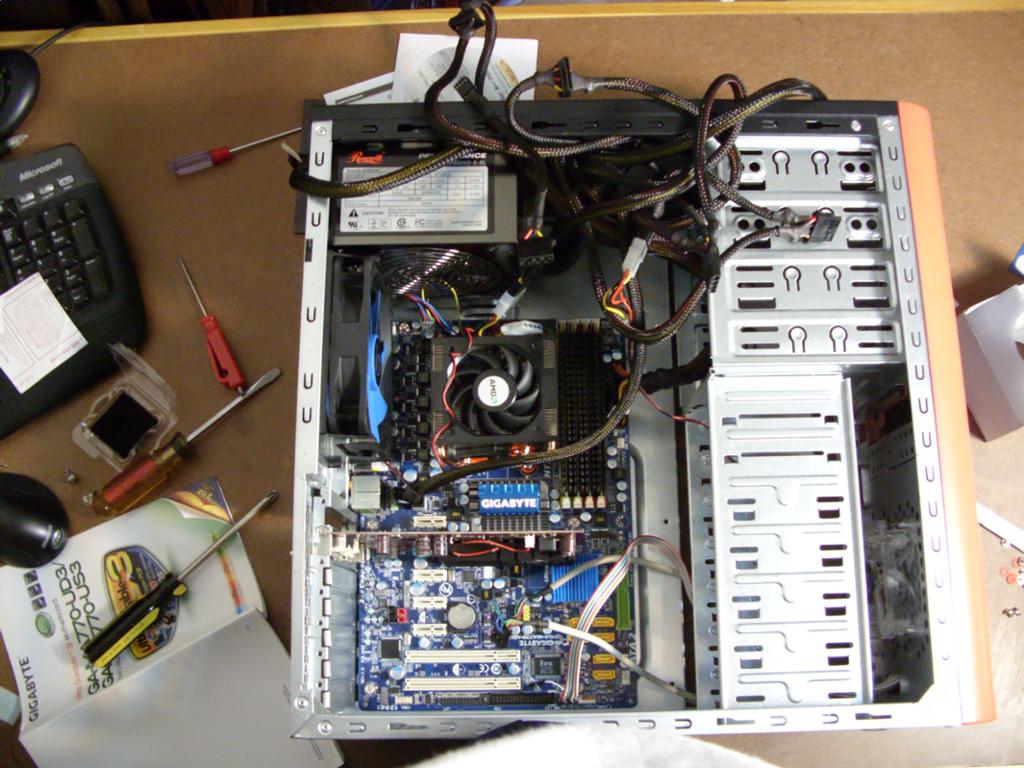 En stasjonær PC blir bygd. I et åpent kabinett ser vi ulike komponenter og ledninger. På bordet rundt ligger det ymse verktøy og skruer. Foto.