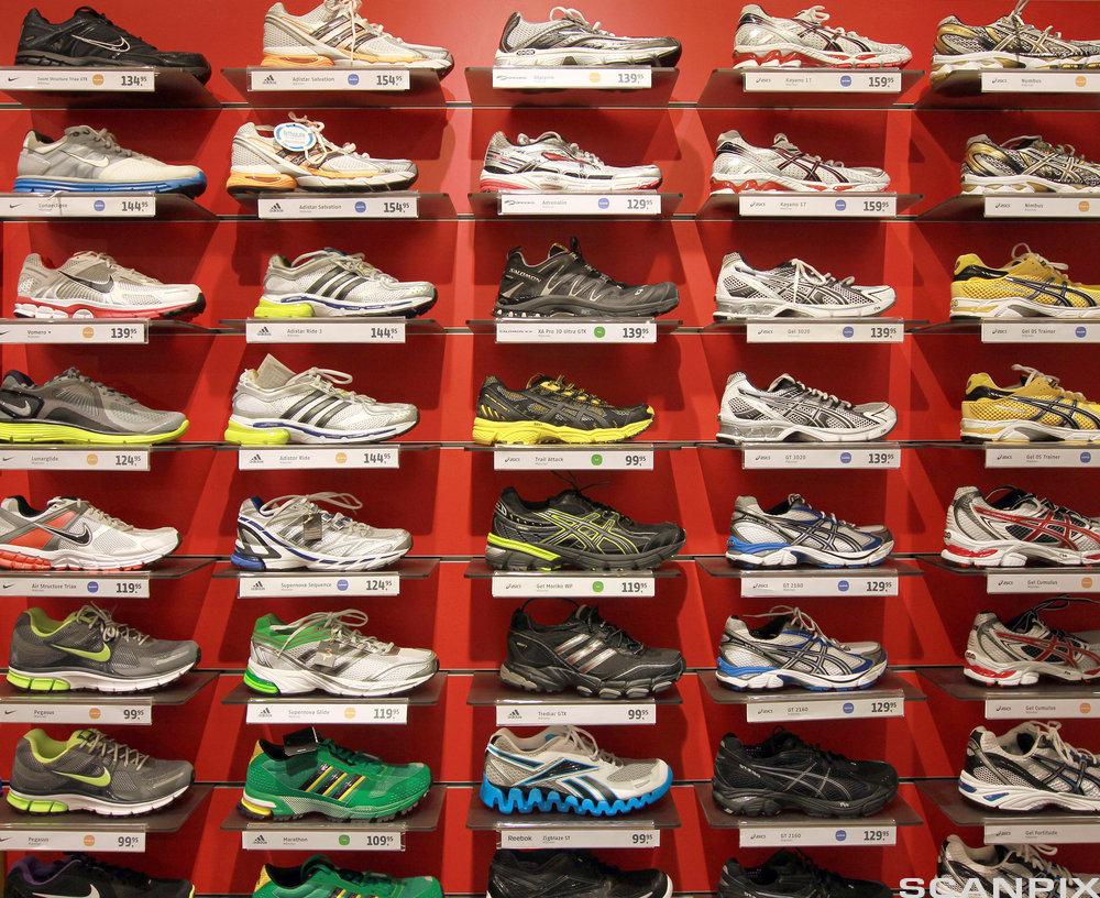 Ulike skopar av typen joggesko oppstilt på hver sin hylle i butikk. Foto.