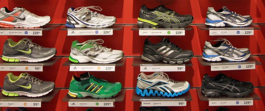 Ulike skopar av typen joggesko oppstilt på kvar si hylle i ein butikk. Foto.