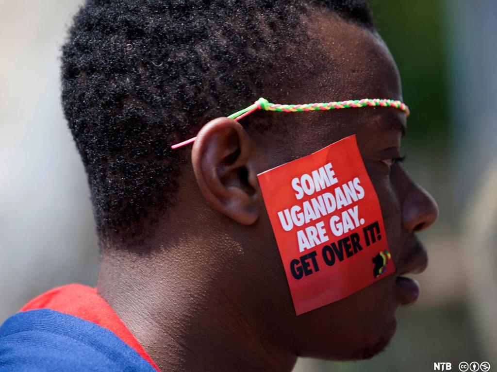 Photo: Black man with a sticker on his face that says 'some Ugandans are gay. Get over it!
