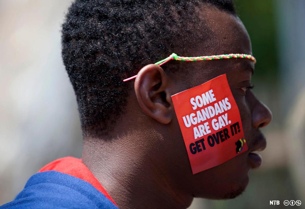 Photo: Black man with a sticker on his face that says 'some Ugandans are gay. Get over it!