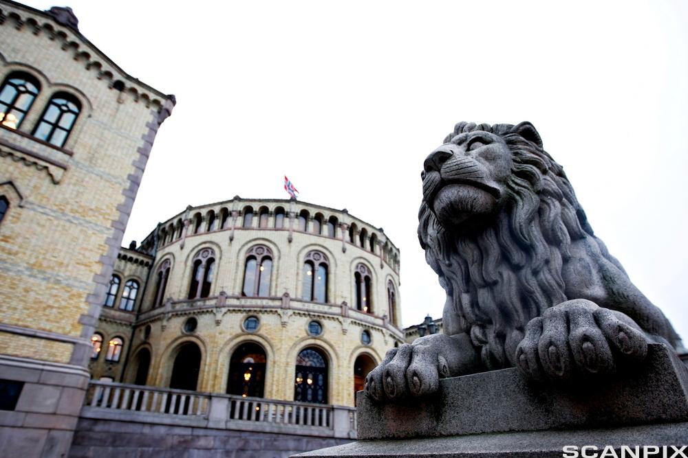 Fasadebilde av Stortinget med løvestatue i forgrunnen. Foto.