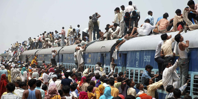 Folkemengde i Asia klatrar opp på taket på eit overfylt tog.  Foto.