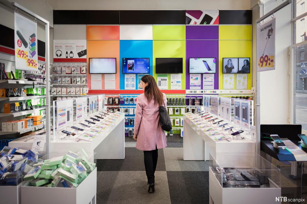 En kvinnelig kunde kikker på mobiltelefoner i en elektronikkforretning. Foto. 