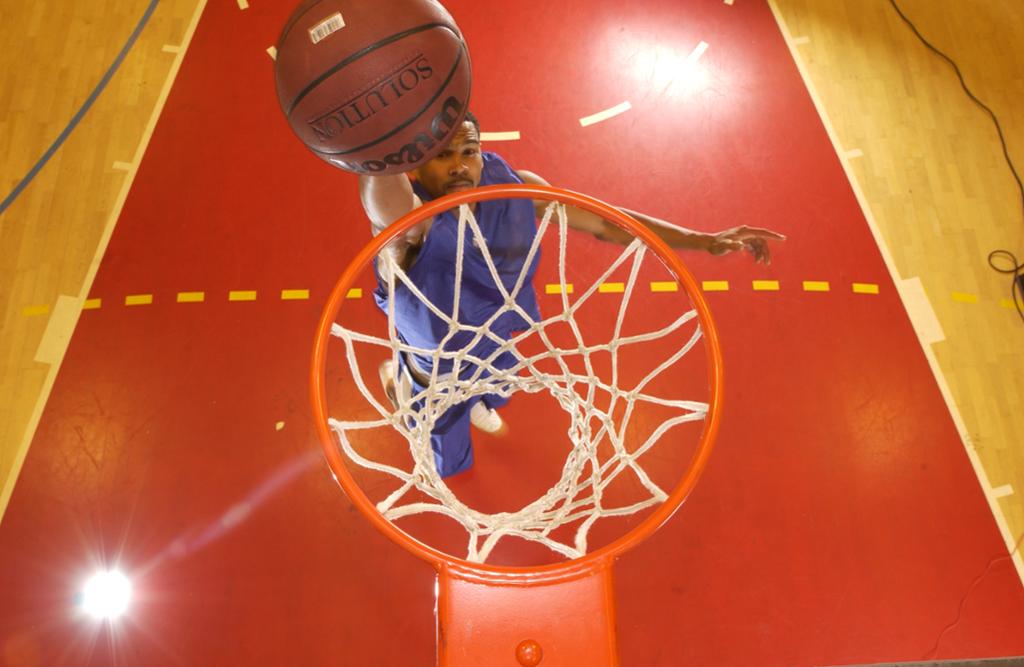 Basketspiller dunker basketballen i basketkurven. Foto. 