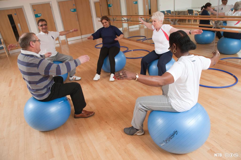 Fem personer trener mens de sitter på hver sin balanseball. Foto.  