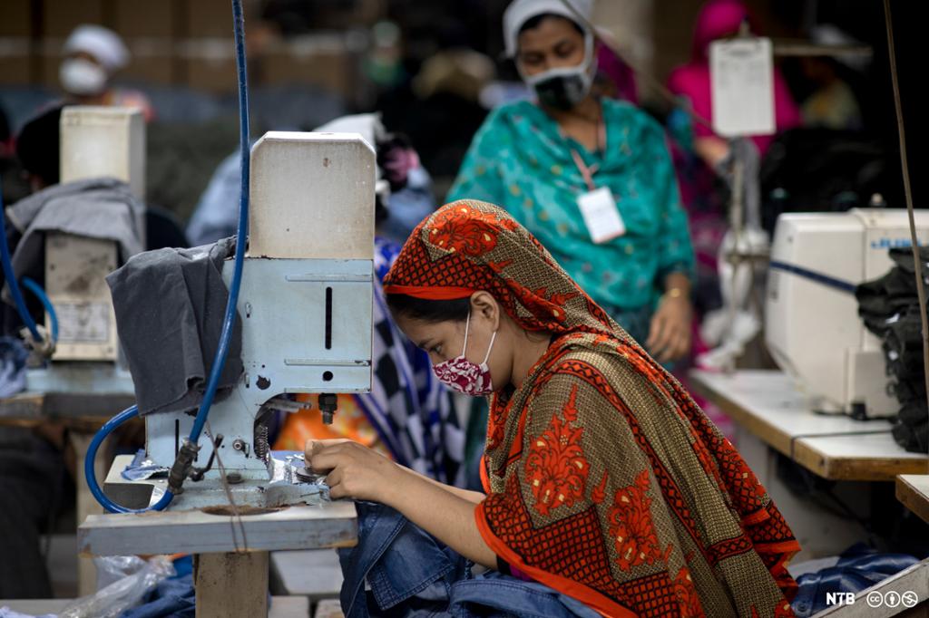 Kvinnelig tekstilarbeider i Bangladesh som sitter ved en symaskin. Foto.