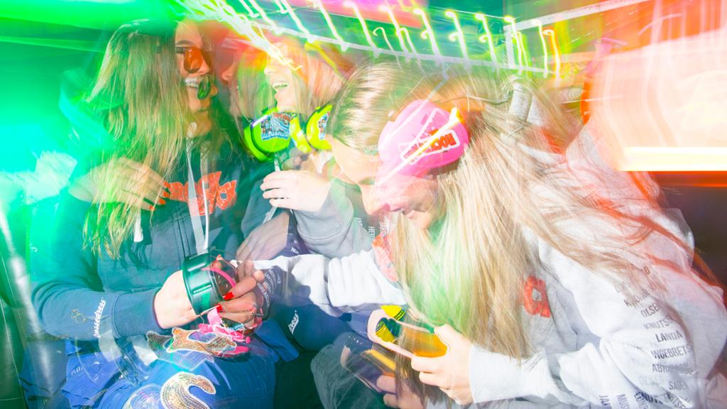 Gutar og jenter i russedressar festar og drikk saman i ein russebuss. Foto.