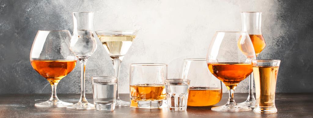 Ulike typer glass som kan brukes til å servere brennevin, står ved siden av hverandre på et bord. Foto.