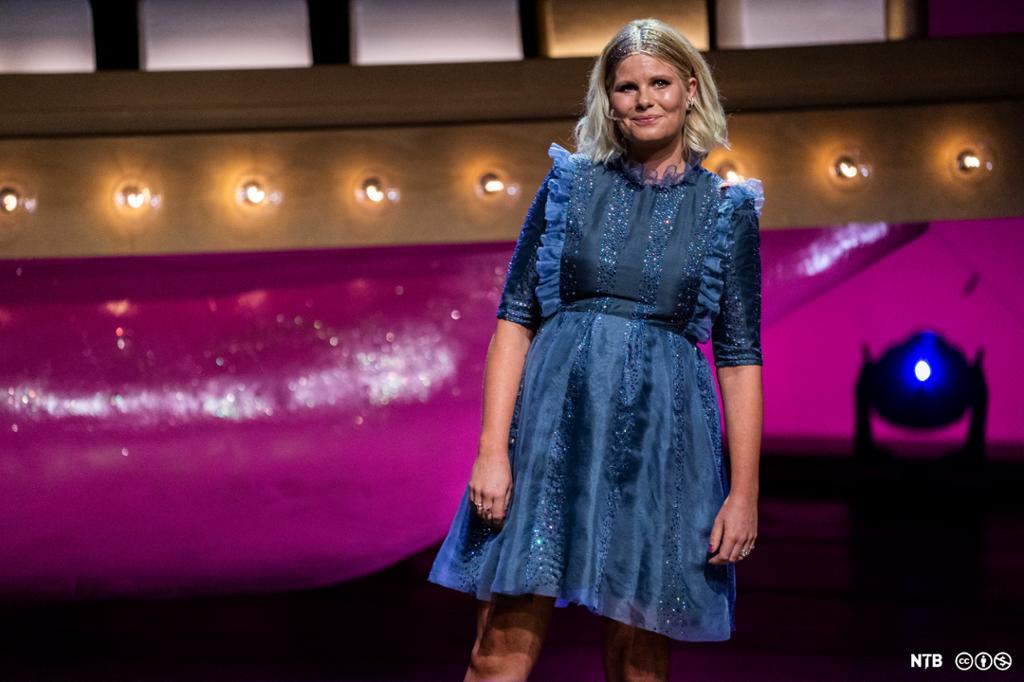 Sofie Linde står på scenen i blå kjole. Foto.