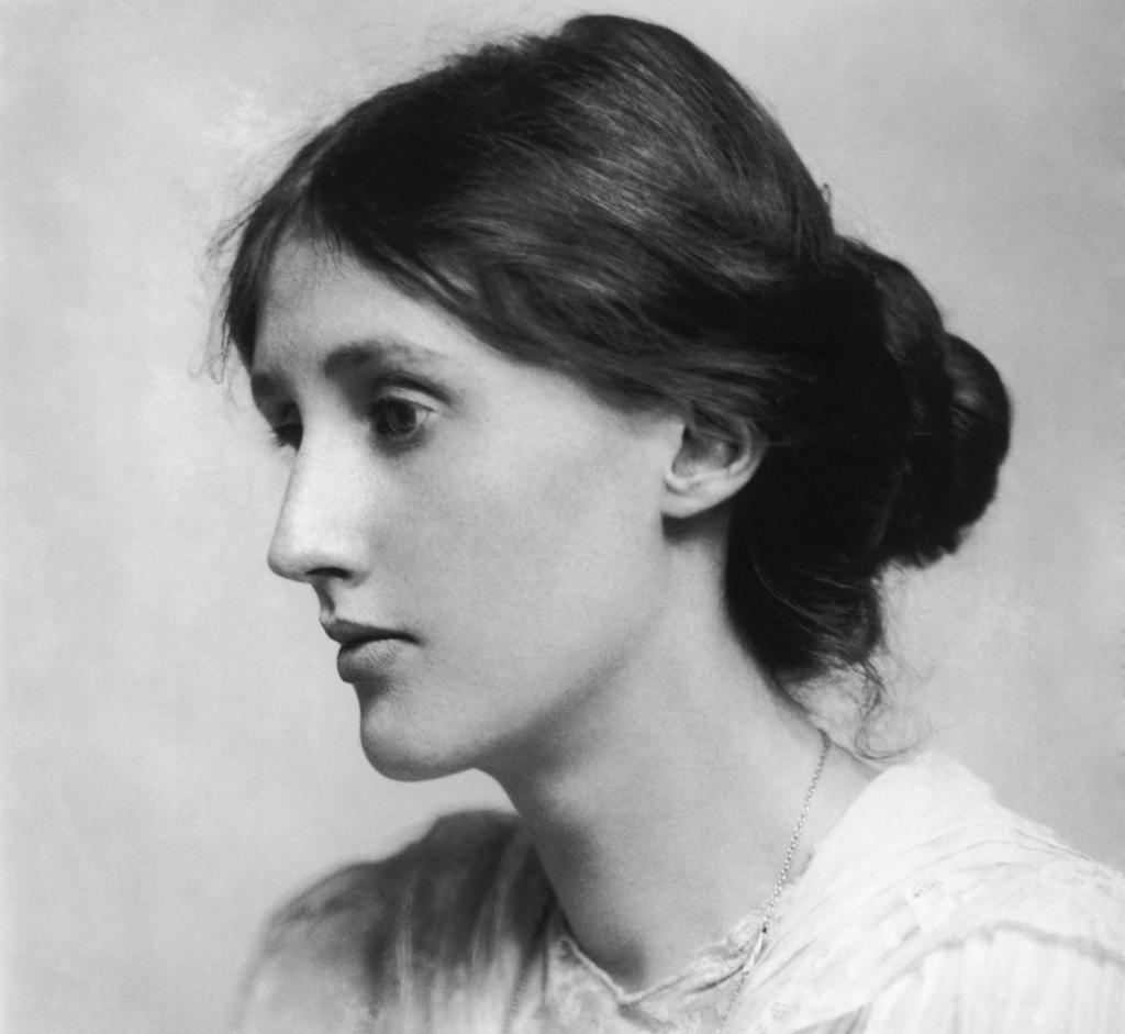 Photo: Portrait of a young woman. She has dark hair, gathered in a bun at the back. She has a serious expression. She is wearing a white blouse. 