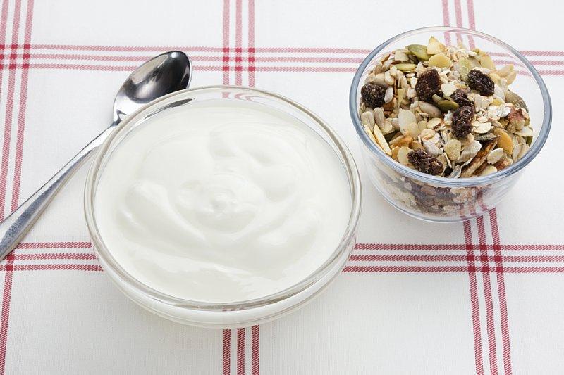Ei skål med yoghurt naturell ved siden av ei mindre skål med mysli. Foto. 