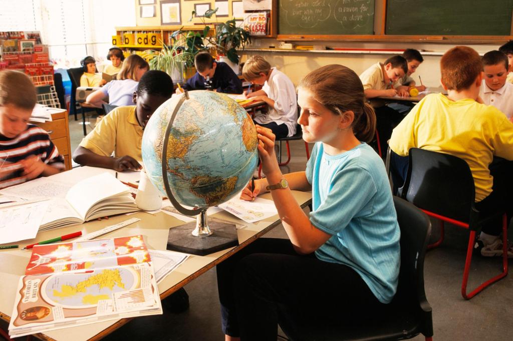 Schoolgirl looking at Africa on a globe. A book (lower left) is open at pages about Victorian Britain and the British Empire. 