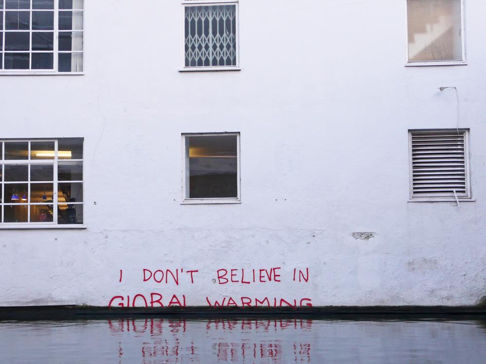 The words 'I don't believe in global warming' is written on a wall, just above the water line. Photo.