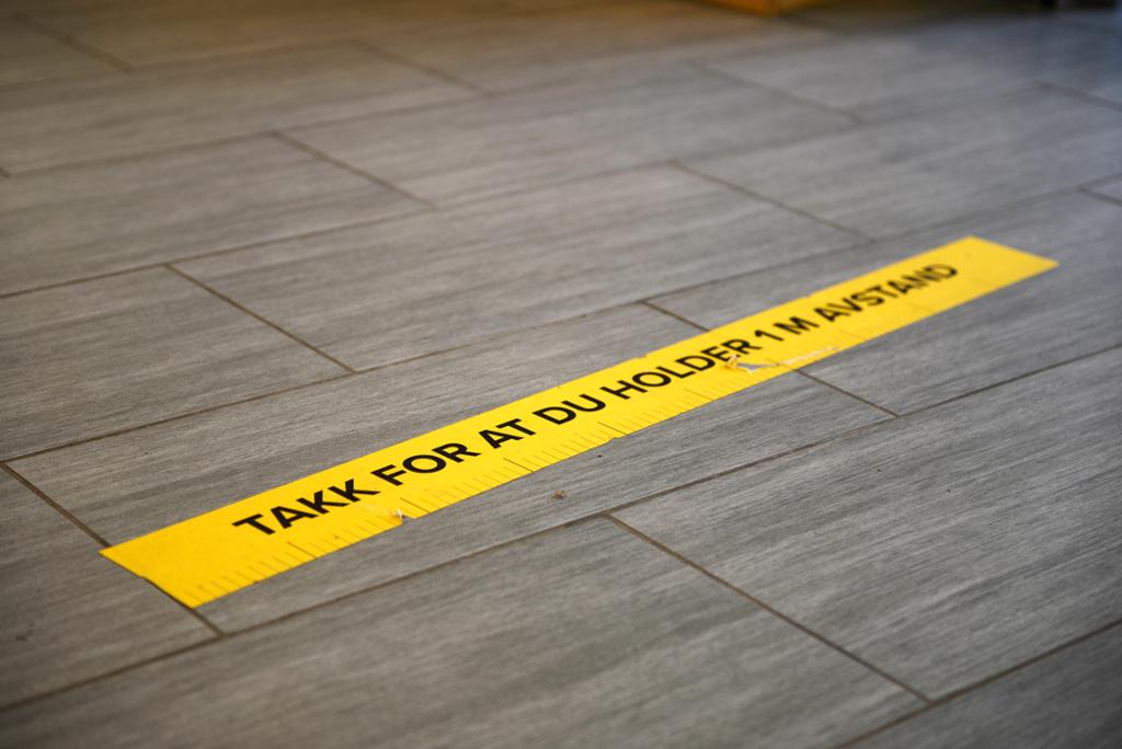Et merke på gulvet hvor det står "takk for at du holder 1 m avstand". Foto. 