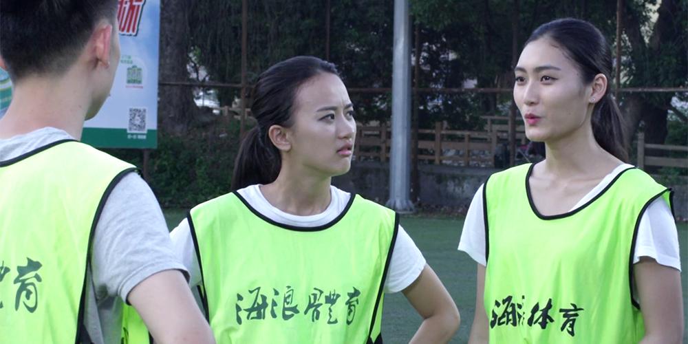 Tre kinesiske studenter med refleksvester på fotballbanen. Foto.