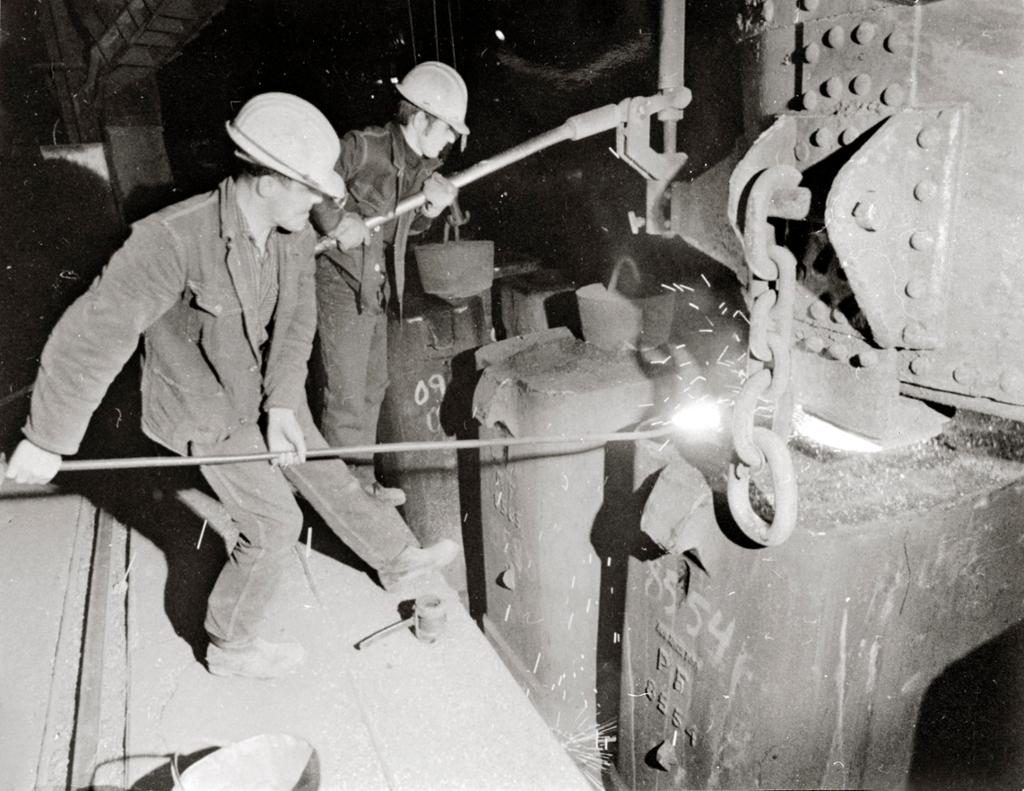 Bildet er fra 1970-åra. To menn opererer smelteovnen ved Norsk Jernverk. Foto. 