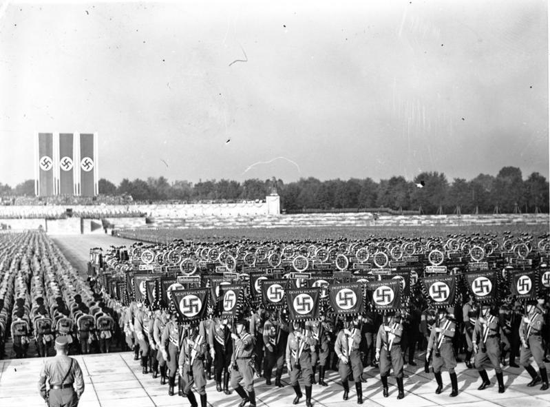 Massemønstring med faner og flagg med hakekors under den nazistiske rikspartidagen i Nürnberg i 1938.