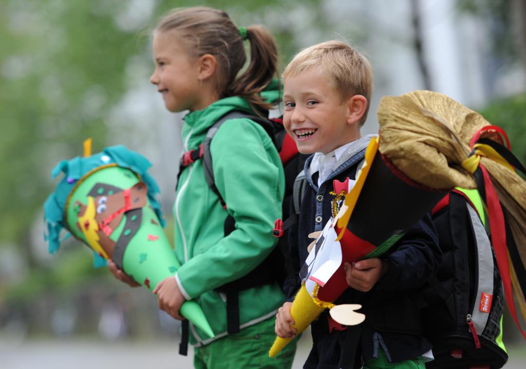 To barn på vei til skolen sin allerførste skoledag. De holder hver sin "Schultüte" i hånden og har sekk på ryggen.